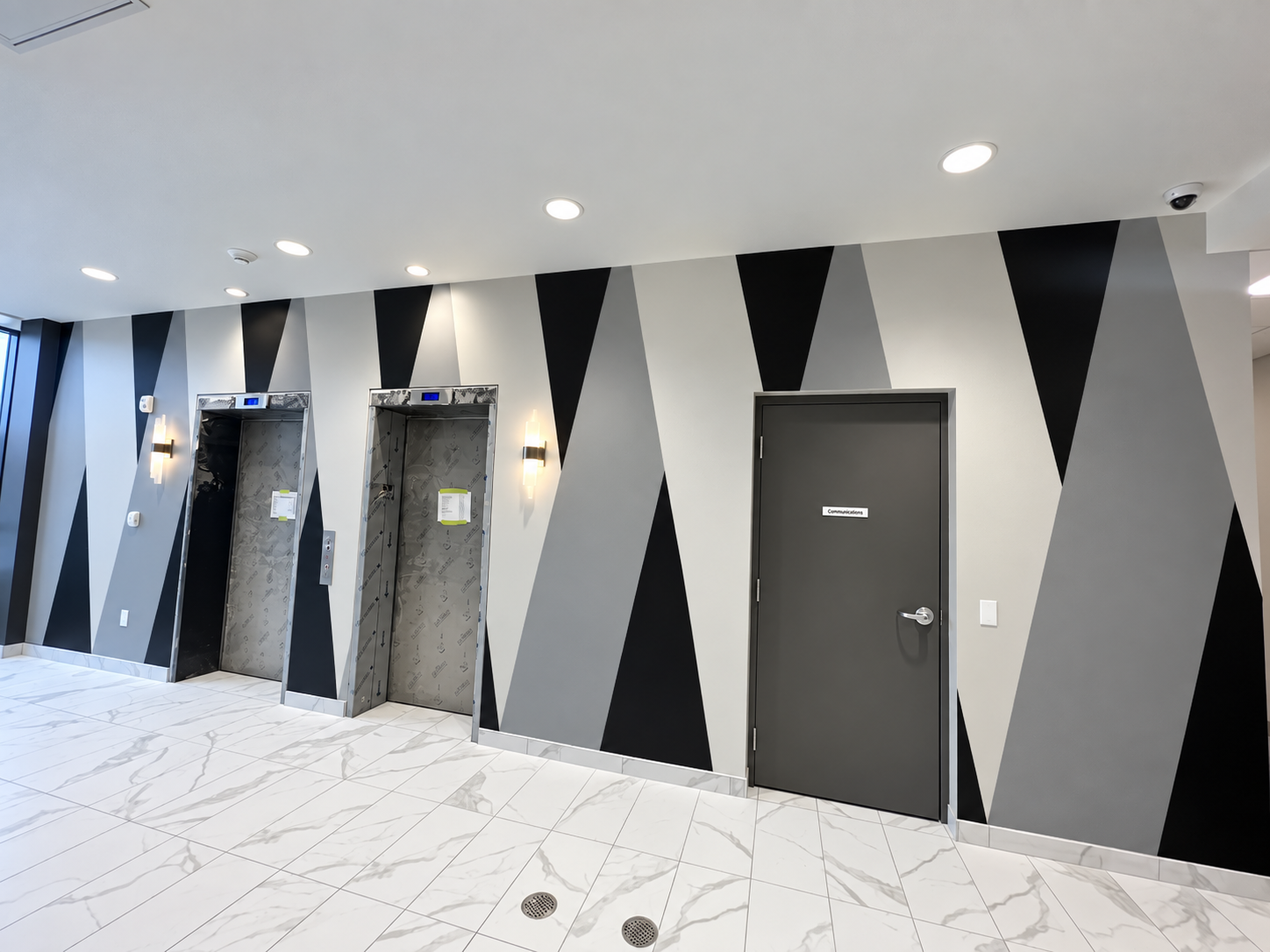 Black and gray geometric painted wall beside elevator openings